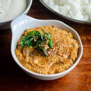 traditional South Indian style Paruppu thogayal served in a white bowl placed over a wooden table. A tempering has been added to the Thogayal