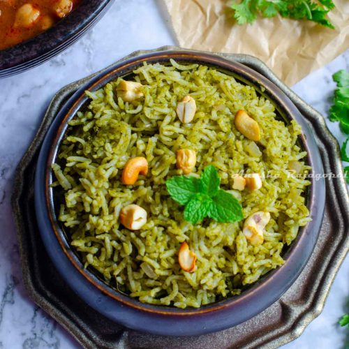 Pudina rice served in a black bowl placed on a metal tray. Cilantro leaves by the side and chole at the far upper left corner.