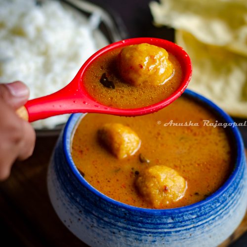 paruppu urundai kuzhambu- South Indian lentil ball gravy served in a white blue bowl.