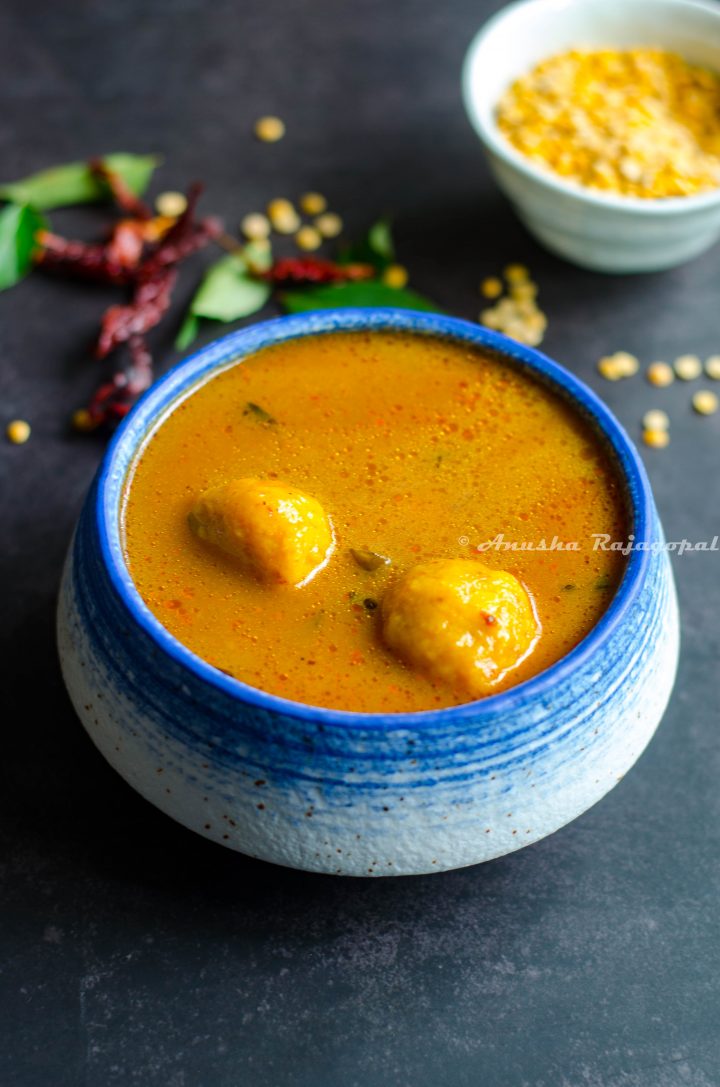 paruppu urundai kuzhambu- South Indian lentil ball gravy served in a white blue bowl.