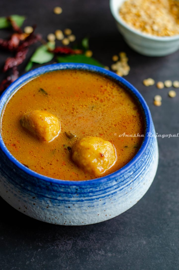 paruppu urundai kuzhambu- South Indian lentil ball gravy served in a white blue bowl.