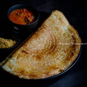 barley dosa served on a black plate with accompaniments
