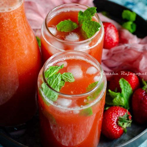 easy fresh strawberry lemonade served in tin can style glasses placed on a metal tray with fresh strawberries and a pink linen cloth around it