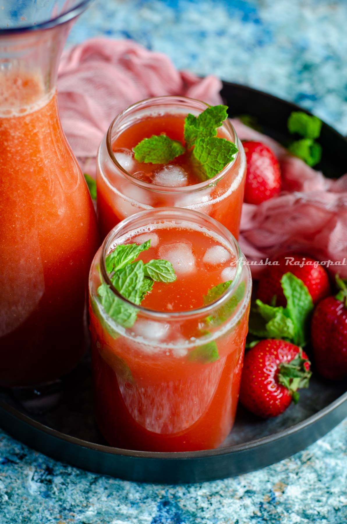 easy fresh strawberry lemonade served in tin can style glasses placed on a metal tray with fresh strawberries and a pink linen cloth around it