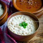 Boondi raita served in a wooden bowl alongside rajma masala