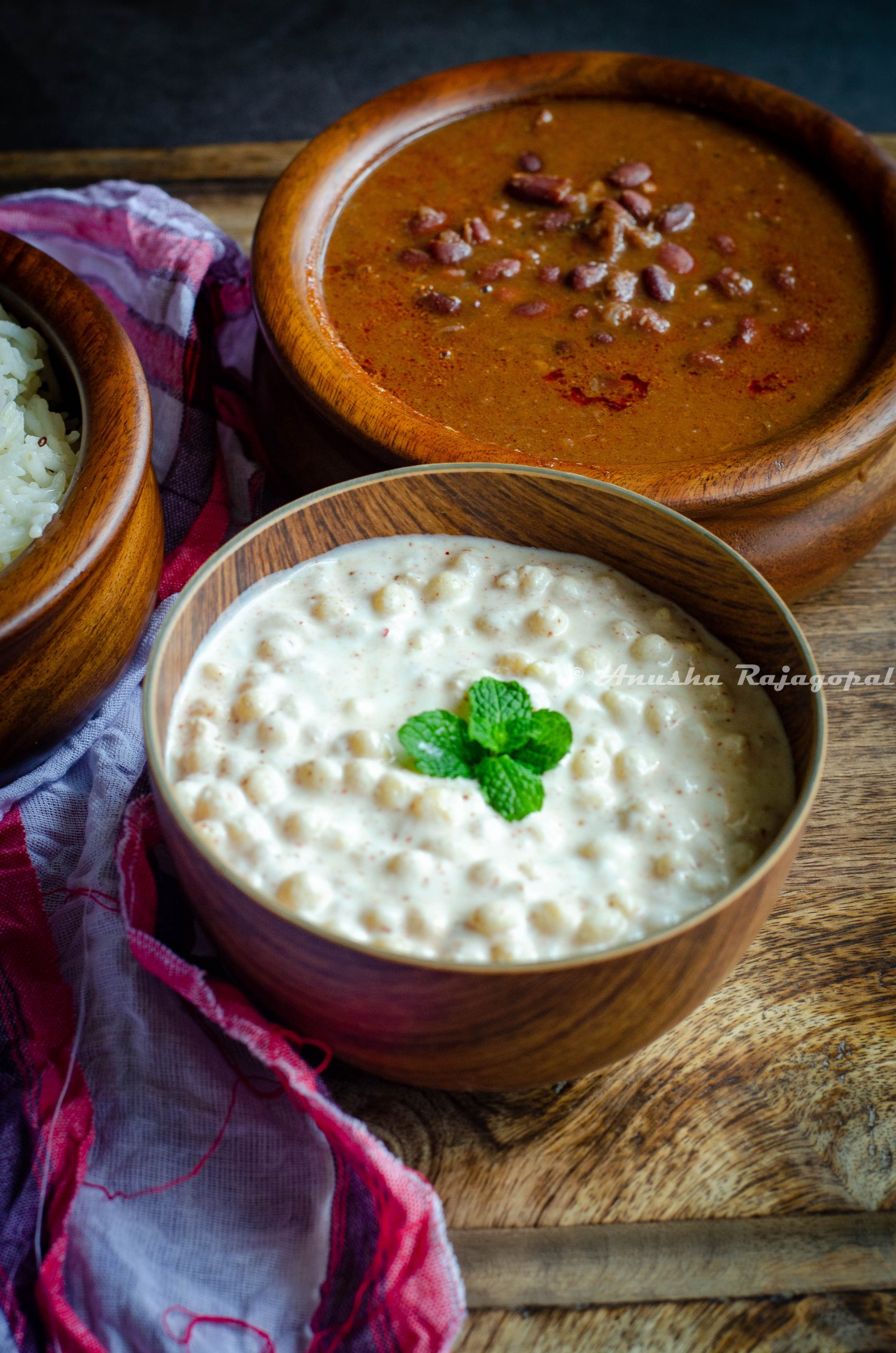 Boondi raita served in a wooden bowl alongside rajma masala