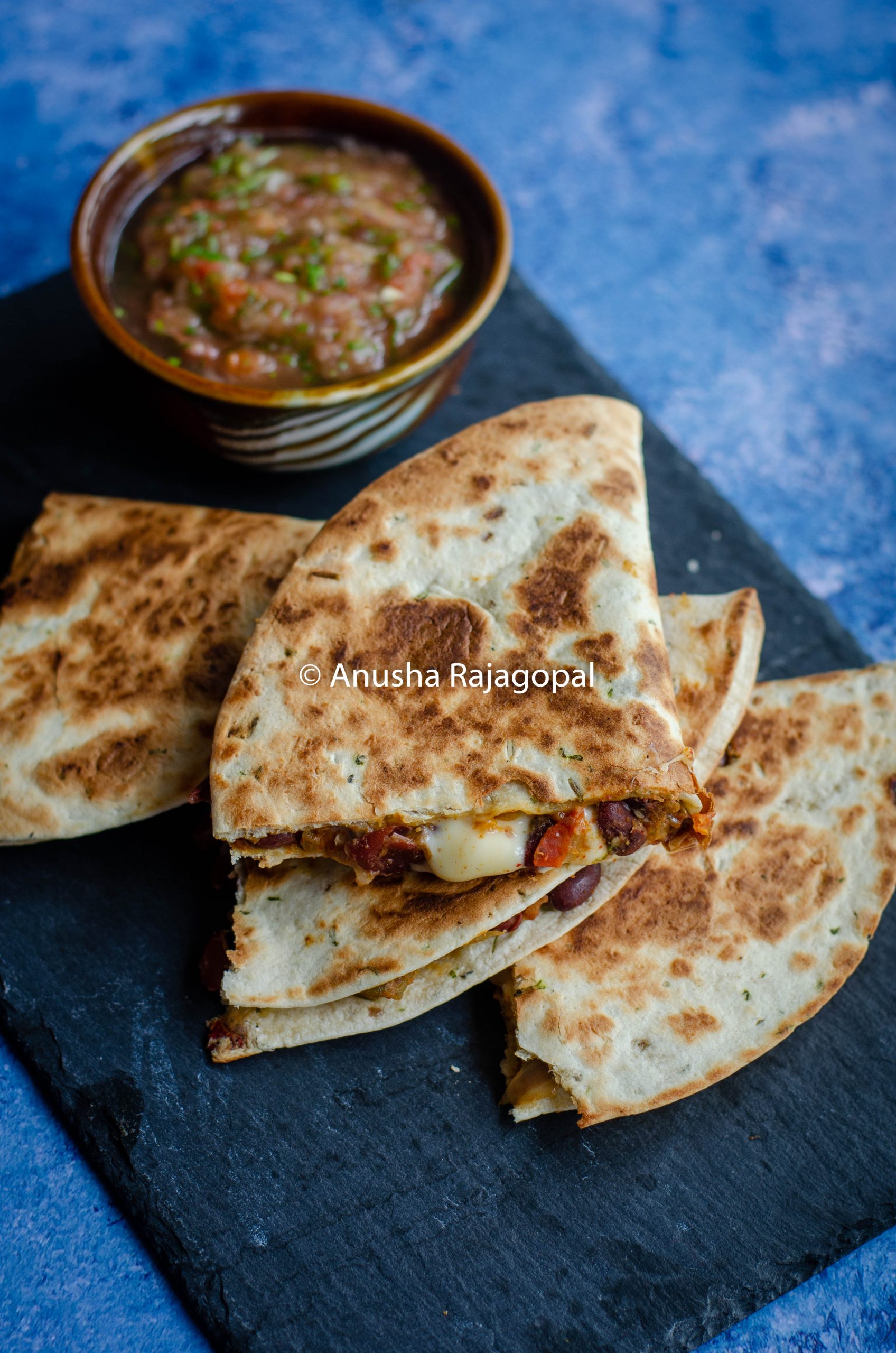 kidney bean quesadilla served with a tomato salsa on a slate board