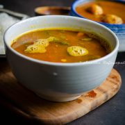 Pineapple rasam served in a white bowl placed on a wooden board