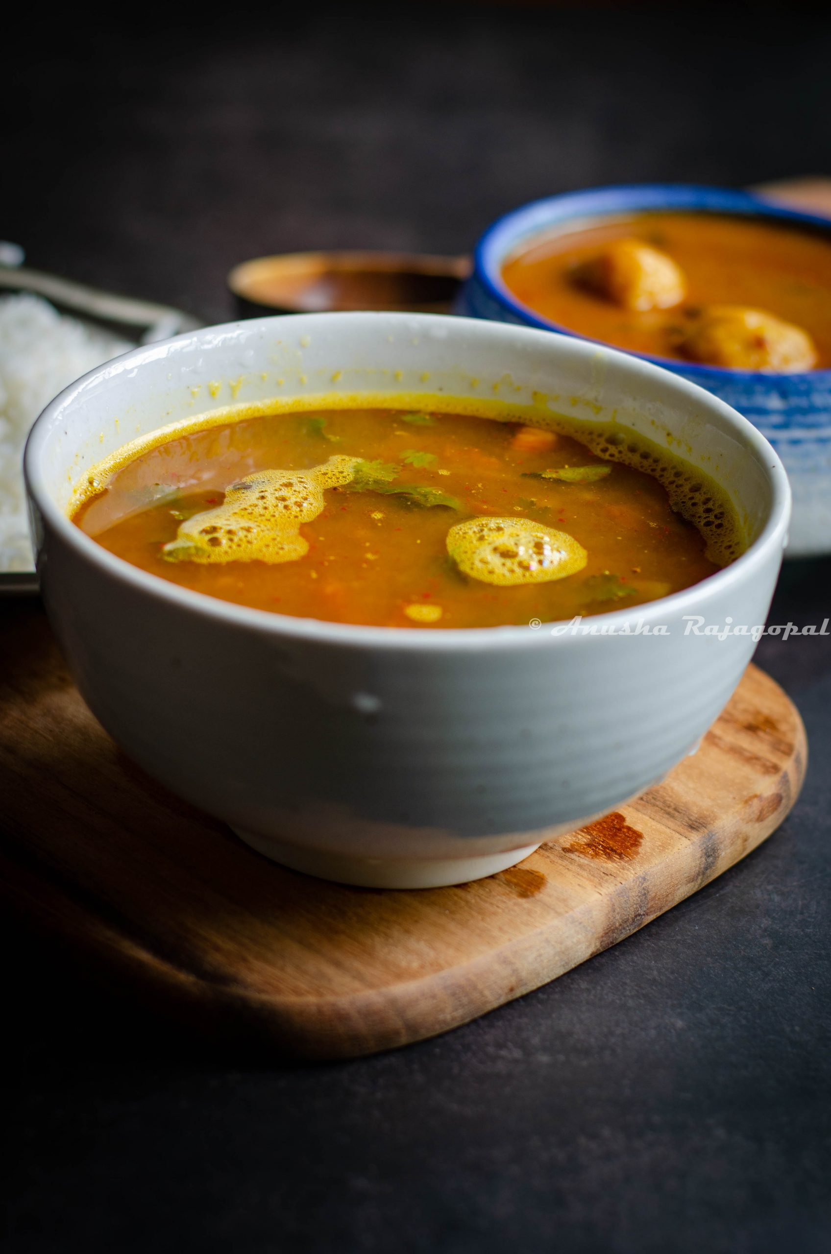 Pineapple rasam served in a white bowl placed on a wooden board