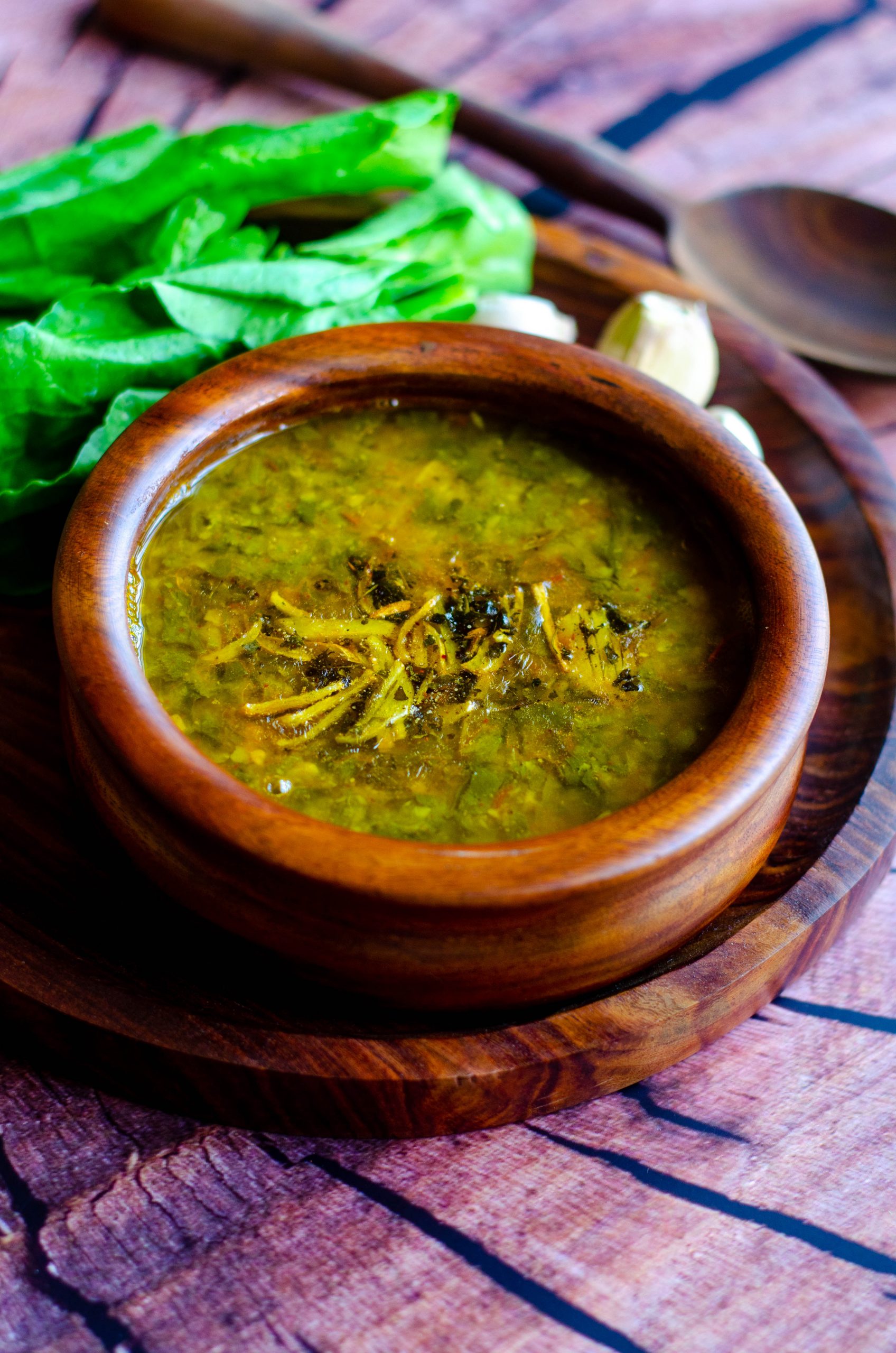 Spinach garlic dal served in a wooden bowl placed on a wooden plate