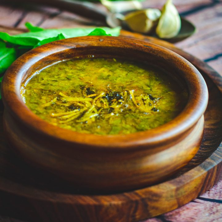 Spinach garlic dal served in a wooden bowl placed on a wooden plate