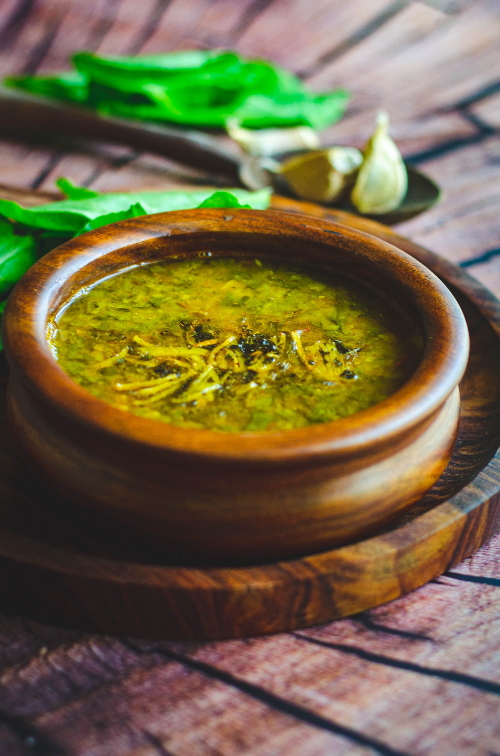 Spinach garlic dal served in a wooden bowl placed on a wooden plate