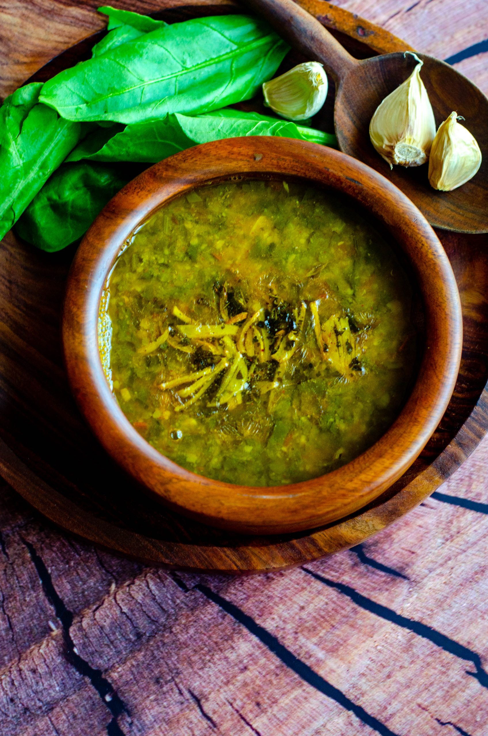 Spinach garlic dal served in a wooden bowl placed on a wooden plate