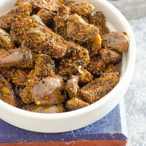 kathrikai podi curry- brinjal stir fry made with fresh spice powder served in a white shallow handled bowl placed on a blue coaster