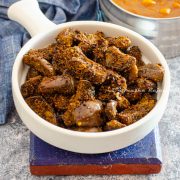 kathrikai podi curry- brinjal stir fry made with fresh spice powder served in a white shallow handled bowl placed on a blue coaster