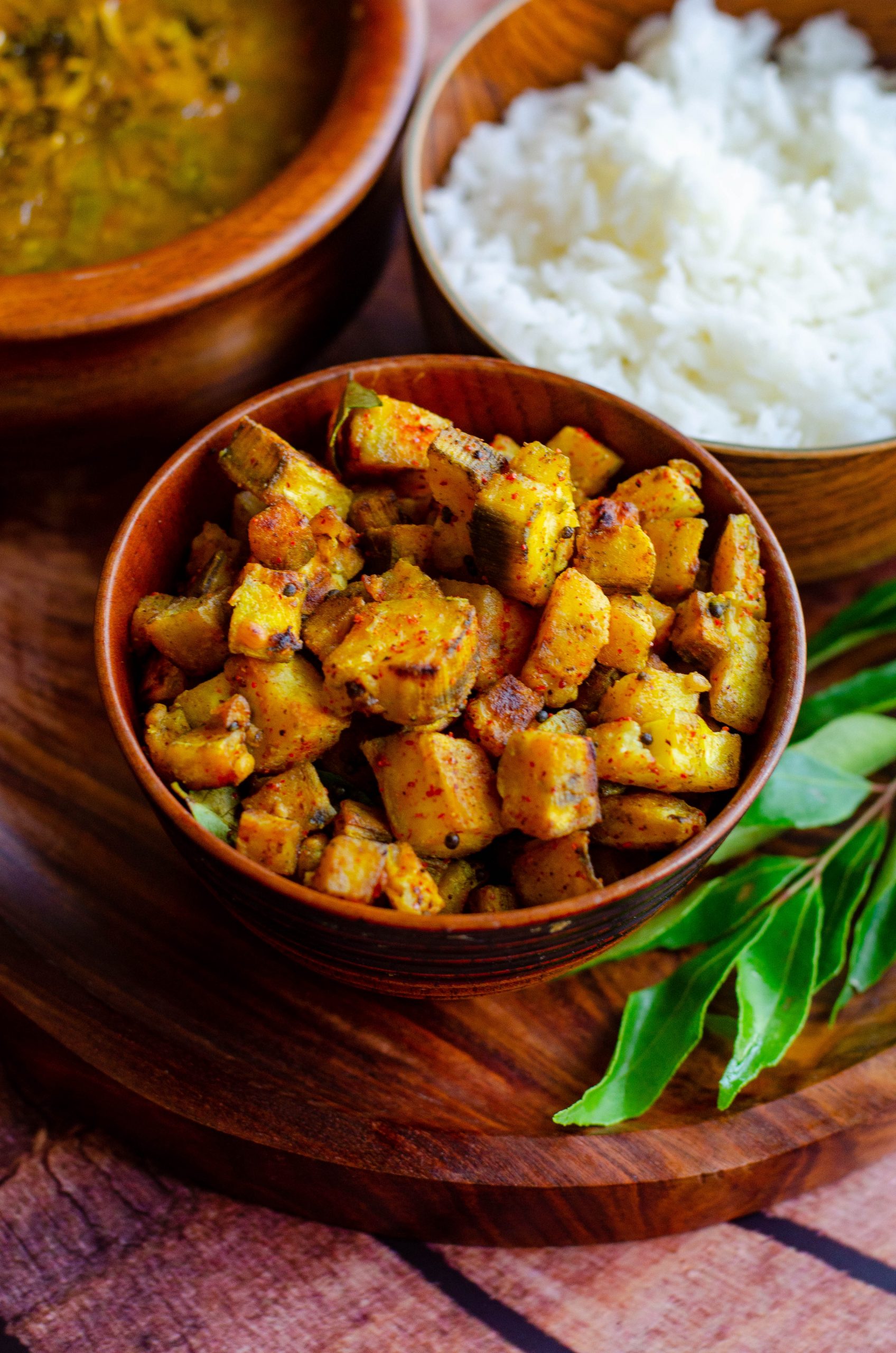 Vazhakai varuval - shallow fried raw plantains served in a wooden bowl with rice and dal