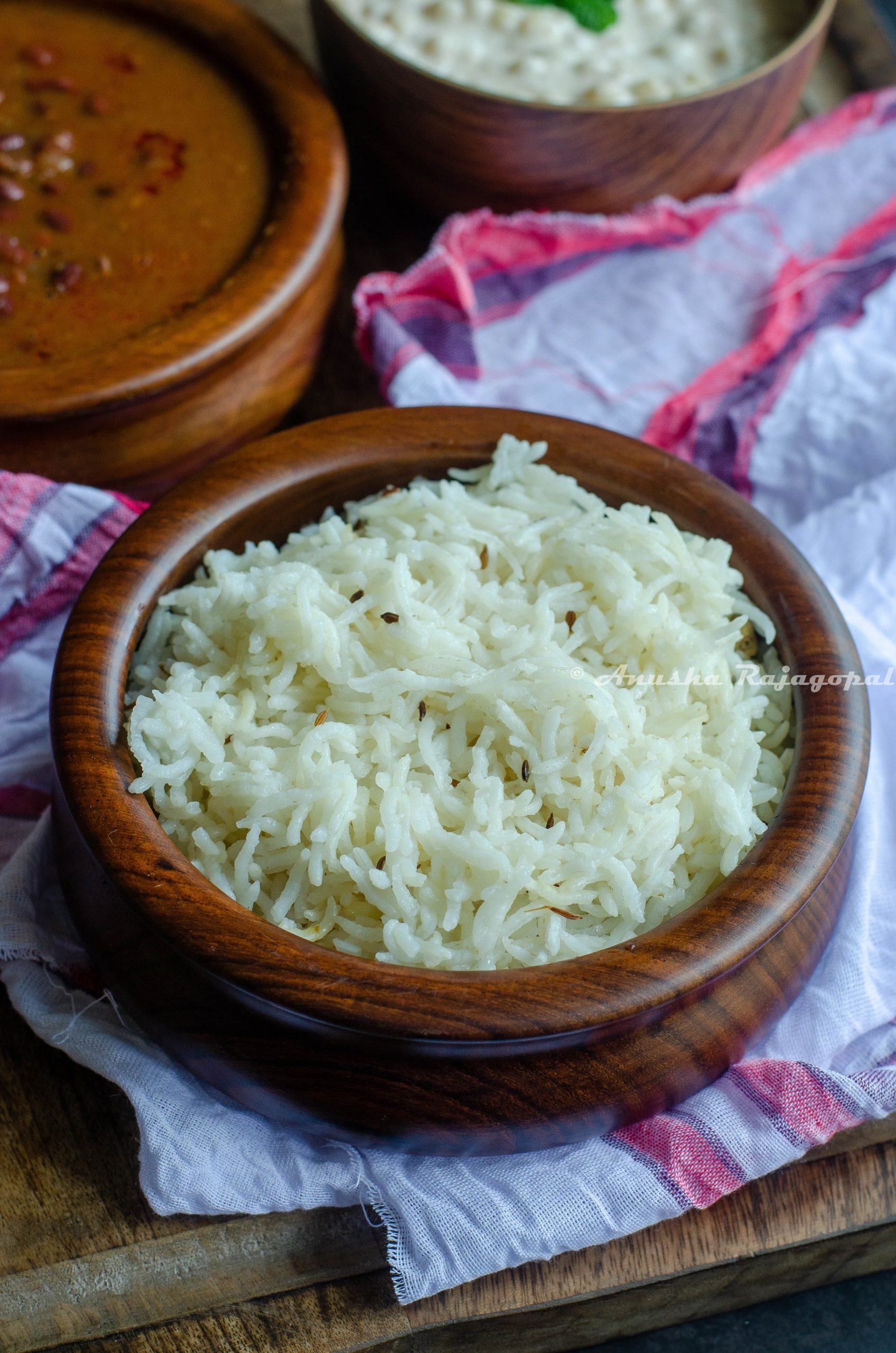 jeera rice served in a brown bowl and placed in a platter with rajma masala and boondi raita