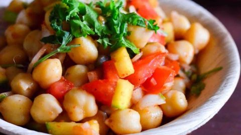Channa chaat served in a beige bowl with cilantro leaves garnished on top