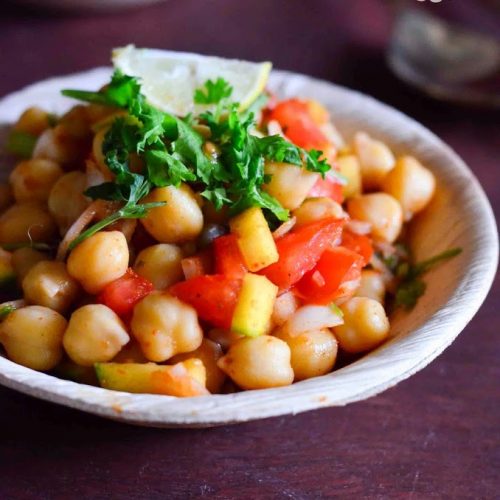 Channa chaat served in a beige bowl with cilantro leaves garnished on top