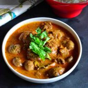 Mushroom Rogan Josh garnished with coriander leaves and served in a white bowl with cumin scented rice