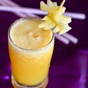 Pineapple Ginger Orange Smoothie Served in a glass on a purple background