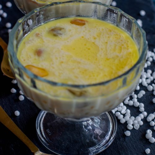 Sabudana kheer- a creamy indian dessert made with sago pearls and milk. Served in a glass bowl placed on slate board.