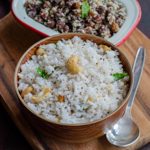 Thengai Sadam, south Indian style coconut rice served along with Kaala channa stir fry. Both placed at an angle to each other on a wooden chopping board.