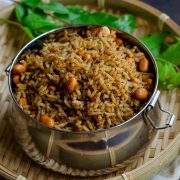 Ellu sadam- A simple vegan rice-based dish made with a sesame seeds based spice mix, served in a tiffin box placed on a bamboo basket against a brown backdrop.