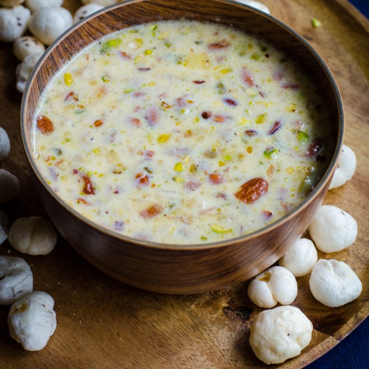 Makhane Ki kheer served in a wooden bowl placed on a wooden plate with makhane in the background