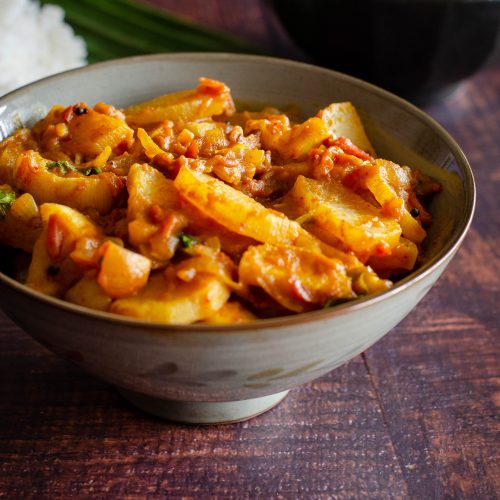 Mullangi Thokku- Radish Masala served in a dull grey bowl placed on a wooden table