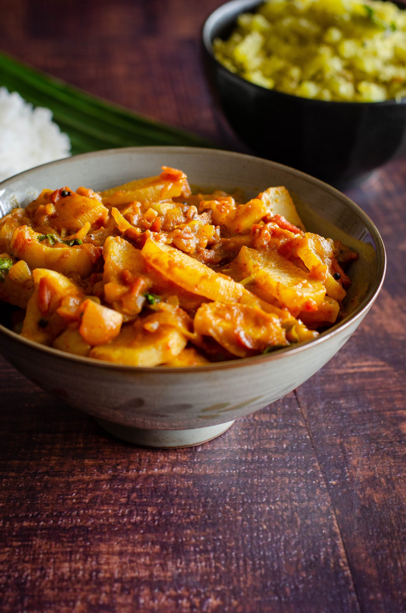 Mullangi Thokku- Radish Masala served in a dull grey bowl placed on a wooden table