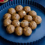 sattu ke ladoo on a black plate with rose petals in the background