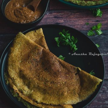 pesarattu- high protein moong beans dosa served on a black plate placed on a table.