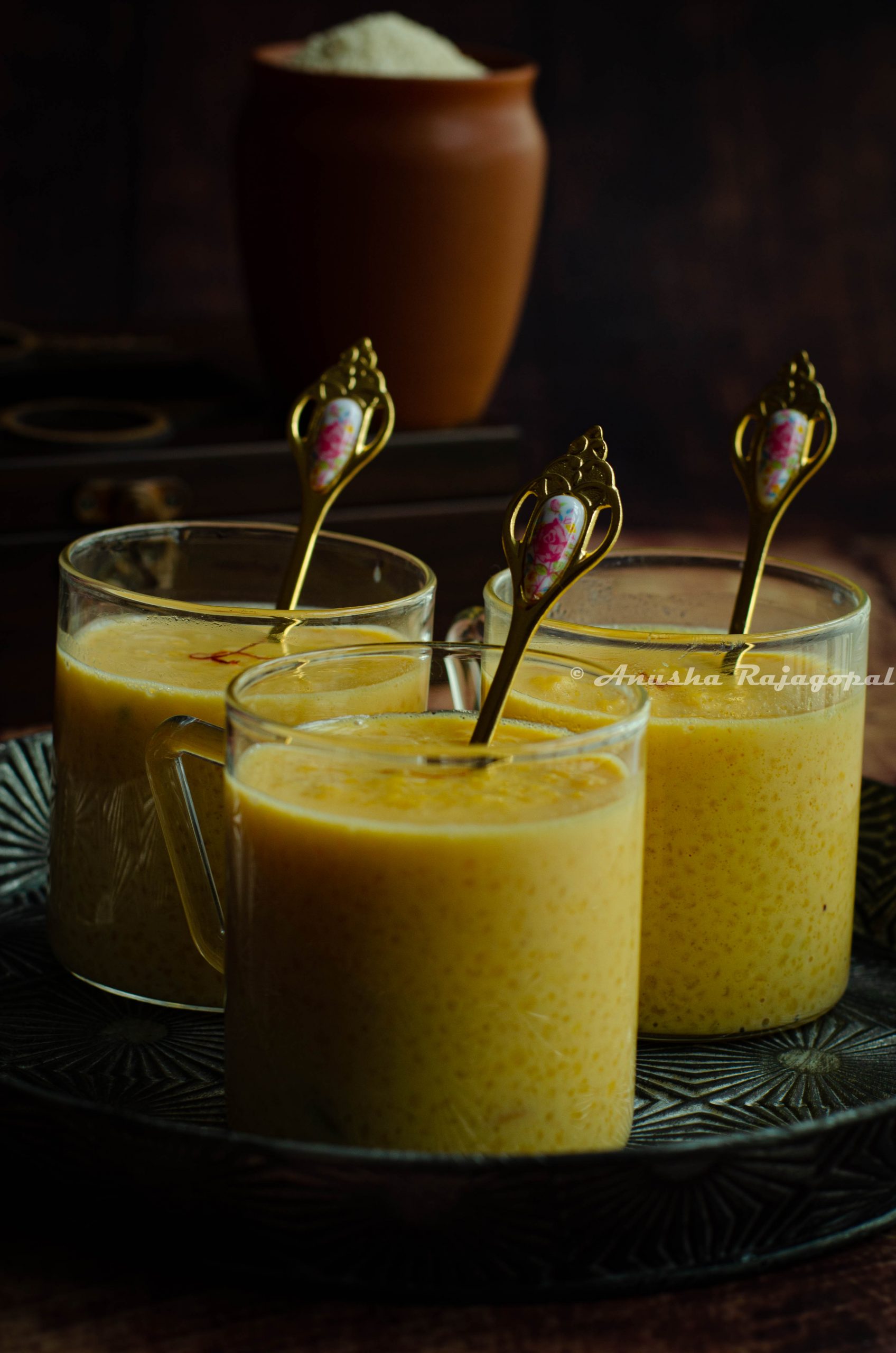 Little millet kheer served in glass mugs with tiny golden spoons in them.