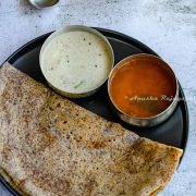 Ragi dosa served with coconut chutney and sambar on a black plate