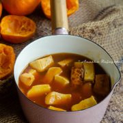 vegan orange tofu served in a pink sauce pan placed on a jute mat