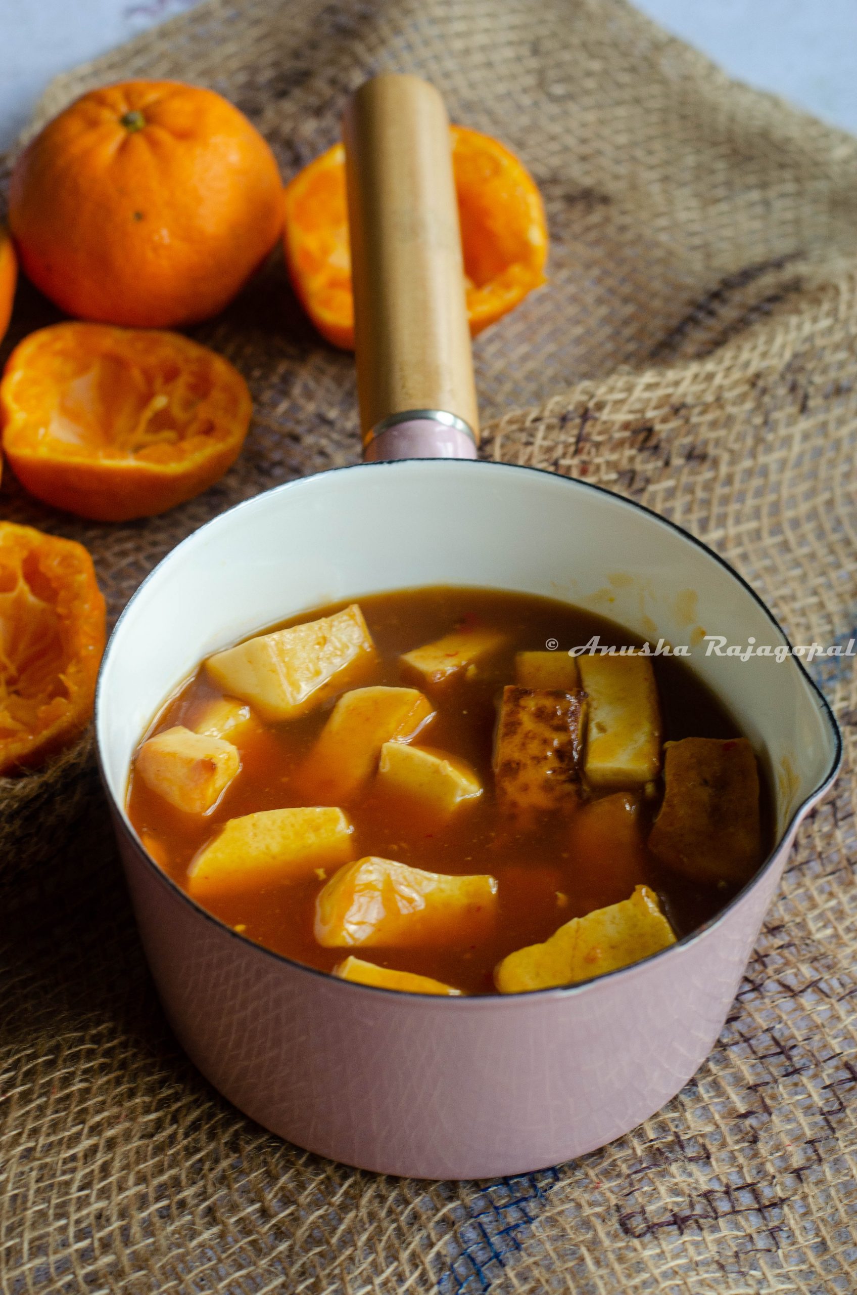 vegan orange tofu served in a pink sauce pan placed on a jute mat