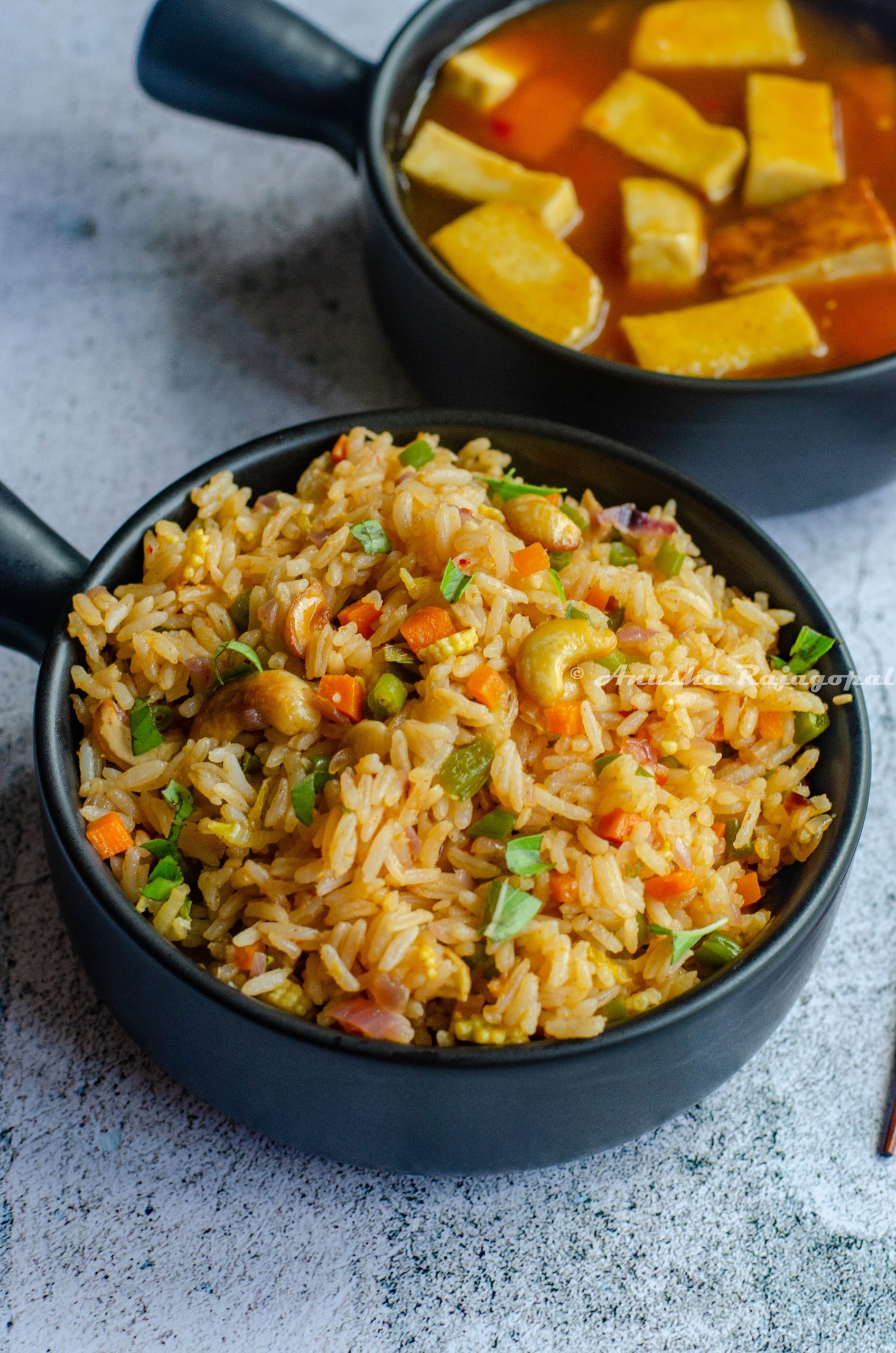 vegan thai basil fried rice served in a black handled bowl alongside orange tofu