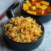 vegan thai basil fried rice served in a black handled bowl alongside orange tofu