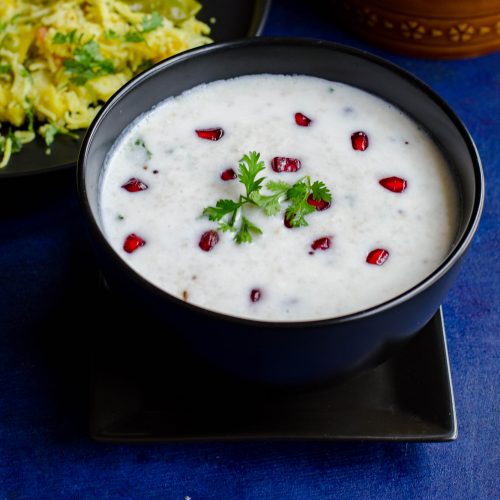 Little millet curd rice served in a black bowl set against a blue backdrop