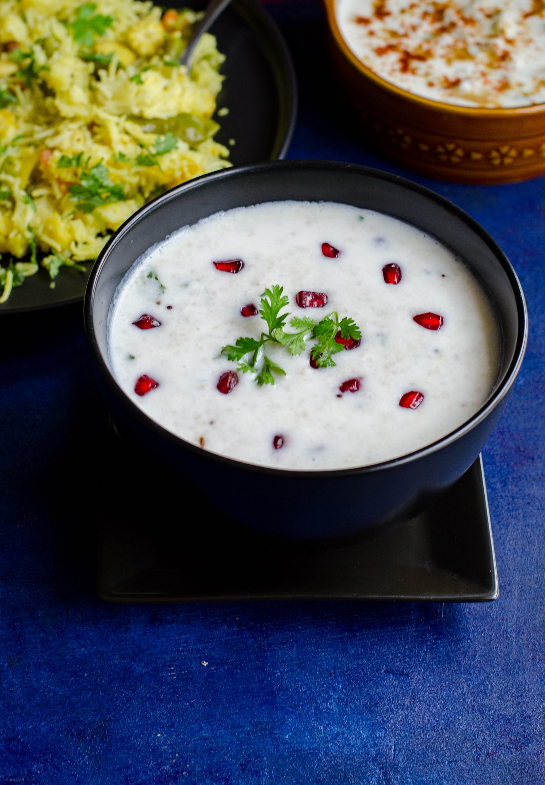 Little millet curd rice served in a black bowl set against a blue backdrop