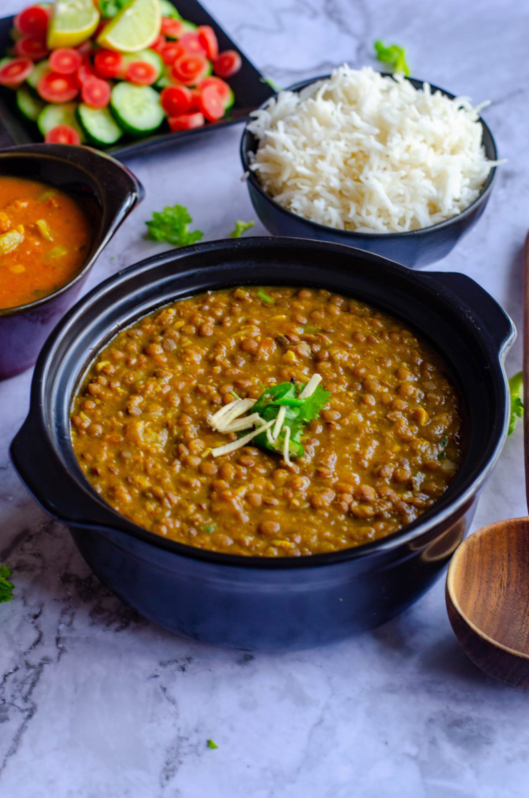 Instant pot whole masoor dal served in a black bowl with steamed rice and salad