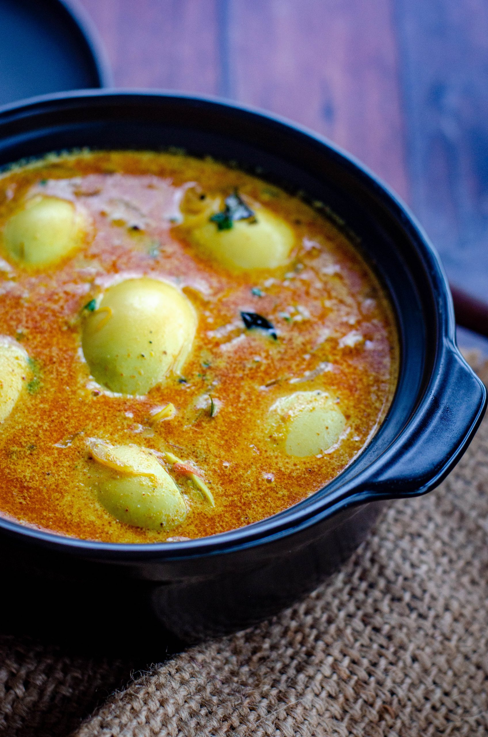 kerala egg curry served in a black bowl placed on a burlap mat