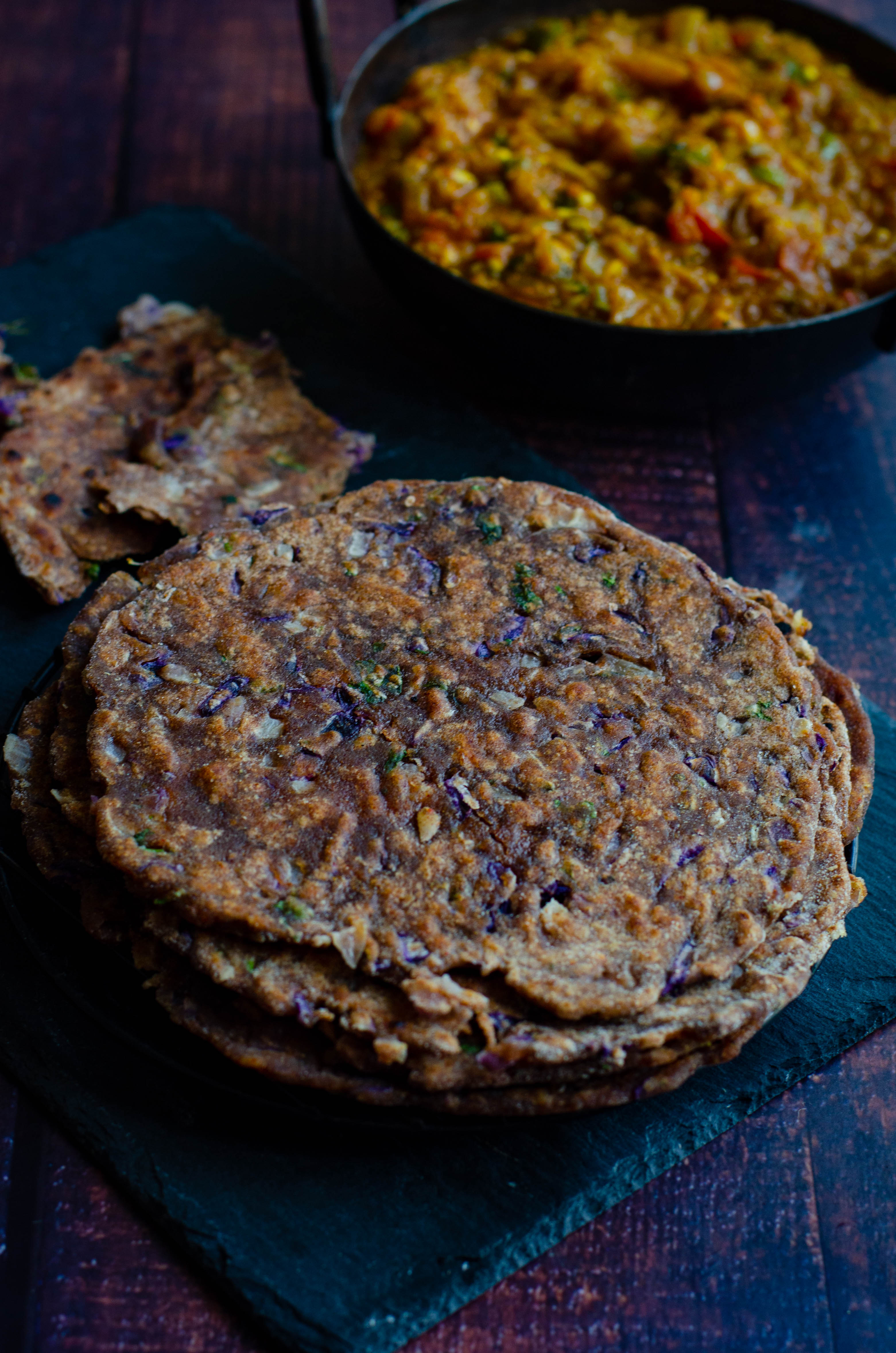 ragi and wheat chapati with purple cabbage stacked and served on a black plate