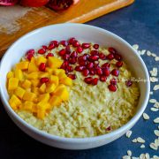 vegan mango overnight oats topped with pomegranate pearls and mangoes