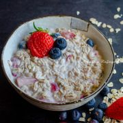 mixed berry overnight oats topped with berries and served in a white bowl