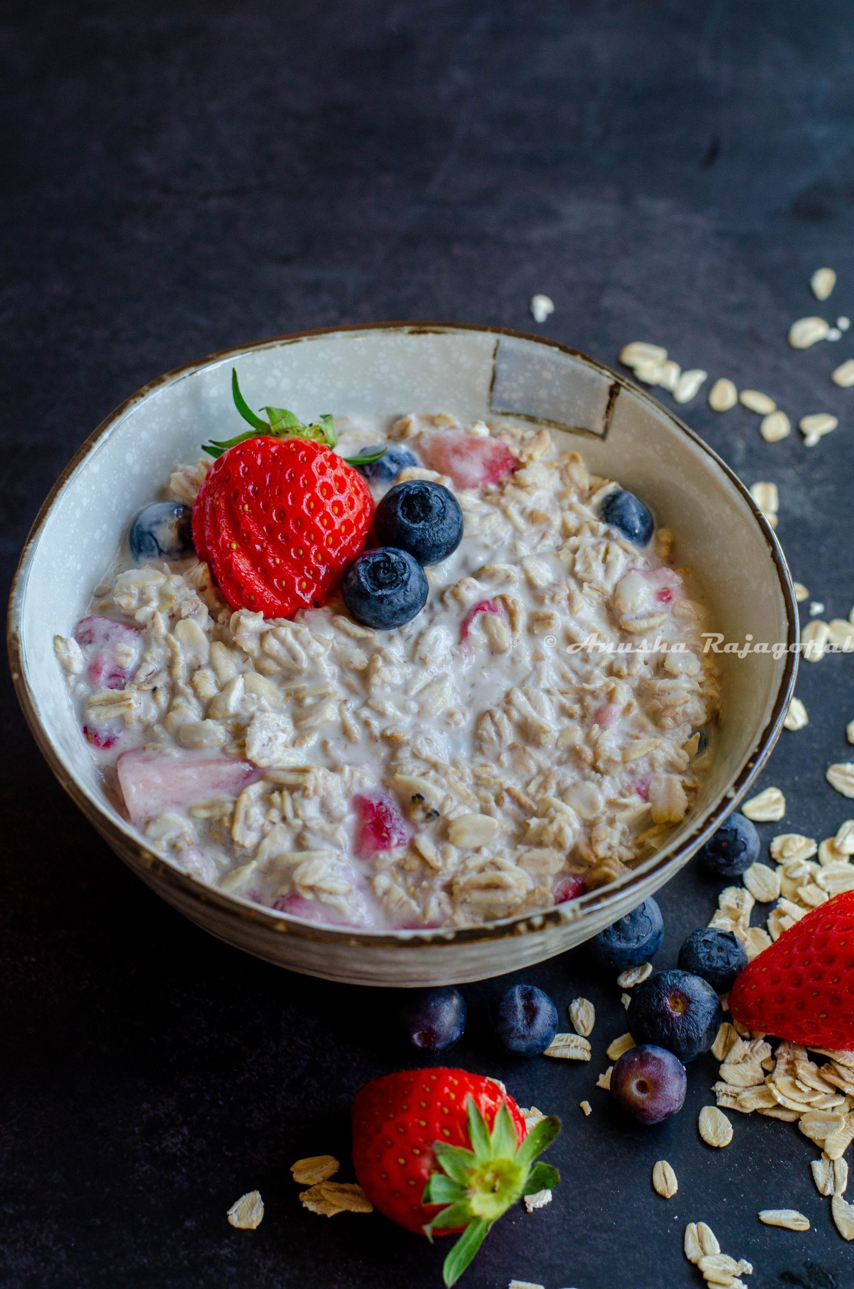 mixed berry overnight oats topped with berries and served in a white bowl