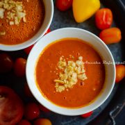 raw vegan tomato gazpacho served in soup bowls with sweet peppers scattered at the background