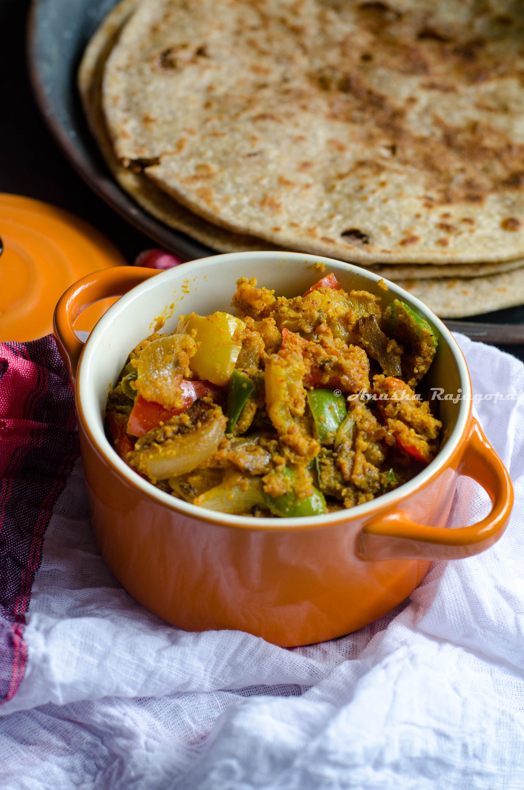 capsicum zunka served in a orange ceramic casserole with parathas