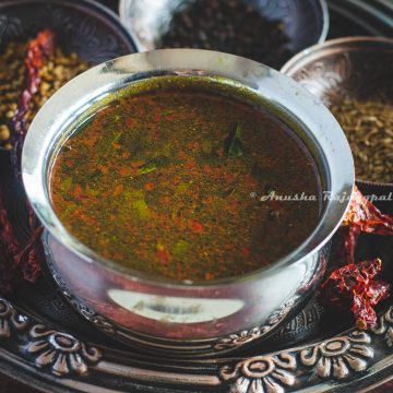 Jeeraga Rasam served in a stainless steel bowl on a vintage tray with spices at the background